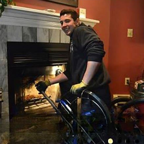 Tech cleaning chimney with vacuum with a light in the firebox.
