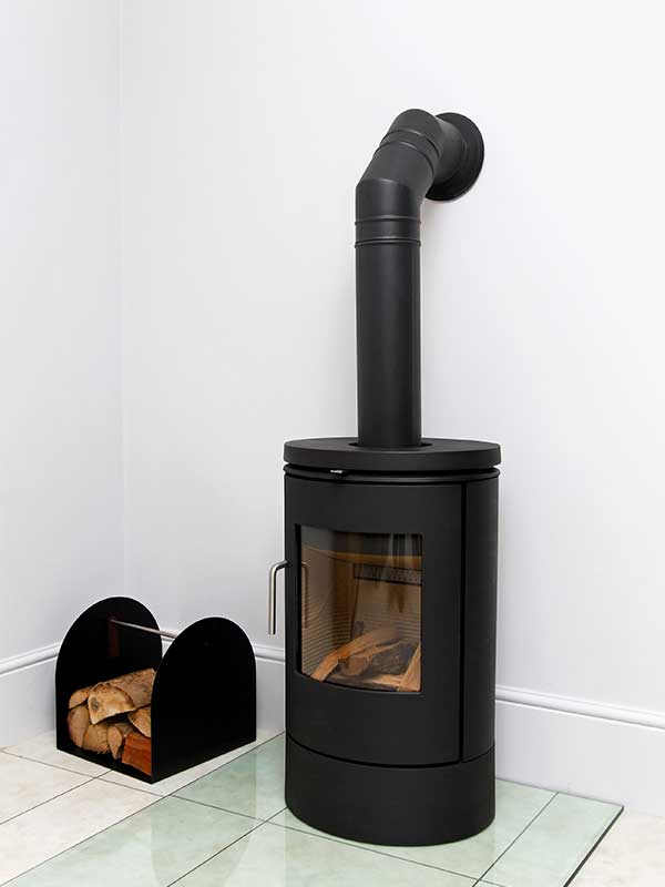 Free Standing Wood Stove - contemporary with a wood holder to the left - stock image - Rutland Chimney.