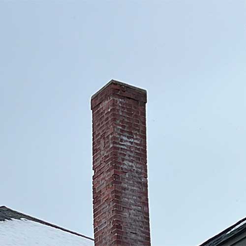 Masonry Repair - Before - has spalling and snow on the roof - stock photo - Rutland Chimney