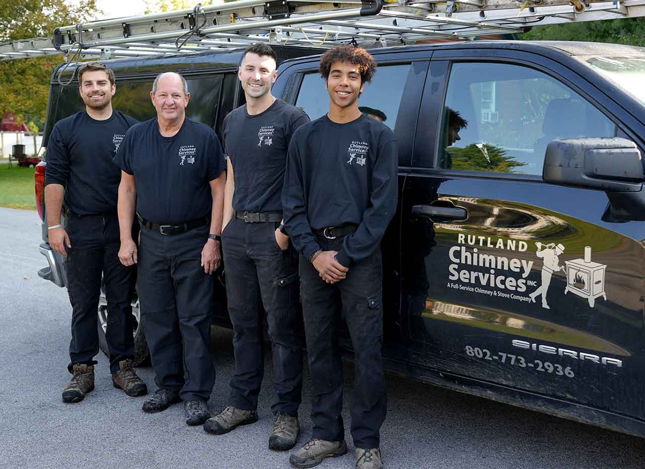 Rutland Team original photo standing in front of truck with logo and a ladder on top.